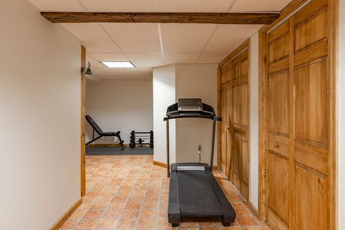 Basement hallway with a treadmill, exposed wood beam and built-in wood cabinetry