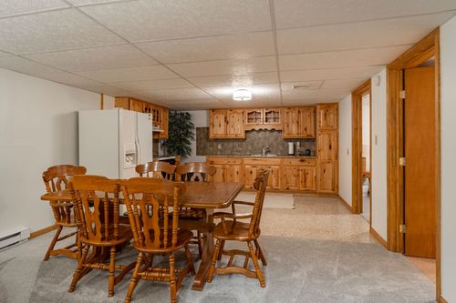 Basement dining and kitchen area with oak cabinets, a farmhouse table and terrazzo flooring