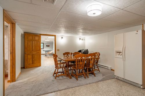 Dining area with a wooden table and chairs beside a stainless double-door refrigerator
