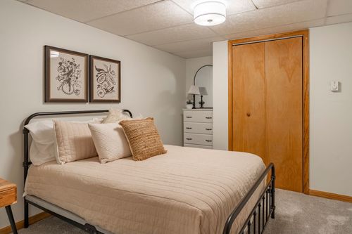 Cozy bedroom with a black iron bed, layered pillows and a round mirror on the dresser