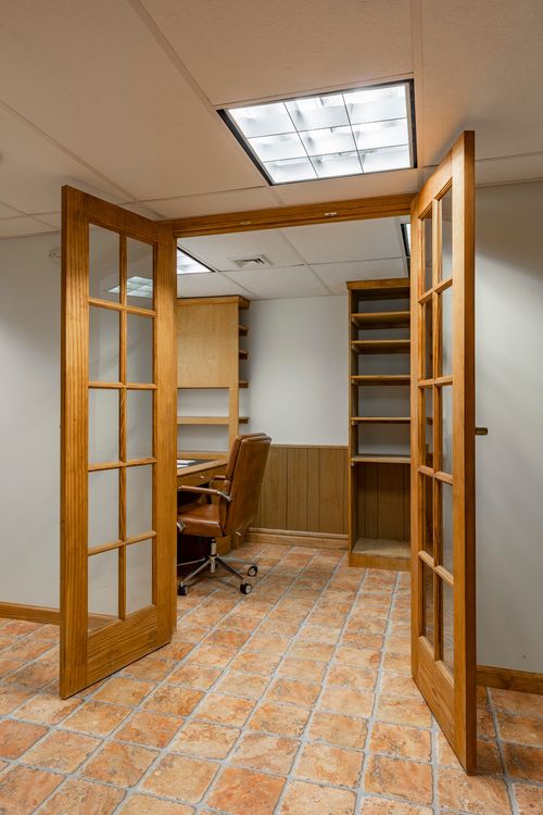 Glass-paneled French doors opening to a home office with built-in shelving