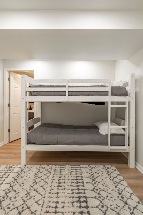 Built-in bunk bed with charcoal bedding and a patterned area rug