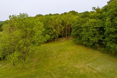 Aerial view of a mowed grass clearing bordered by dense forest