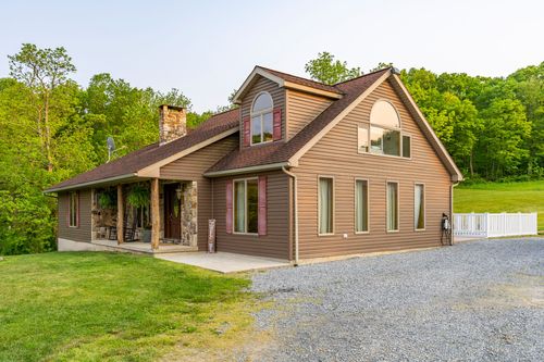 Covered stone porch with a hanging fern, rocking chair and wood front door