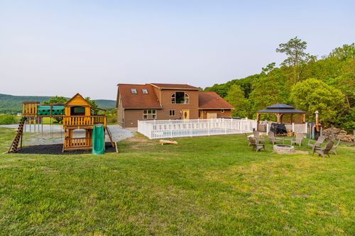 Aerial view of a farmhouse backyard with a play structure, white picket fence and gazebo