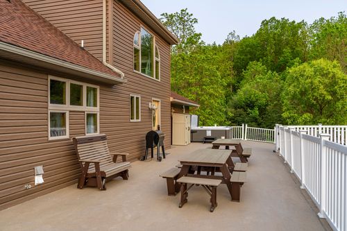 Back deck with a picnic table, bench and grill beside a wood-sided home