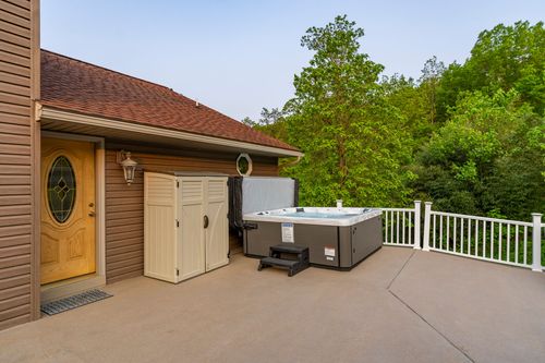 Back patio with a hot tub and storage shed beside a yellow wood door