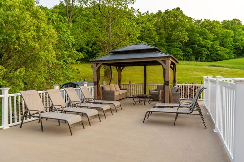Hot tub on a stone patio with white deck railing