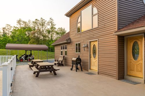 Rear patio with picnic tables beside a farmhouse with an arched picture window