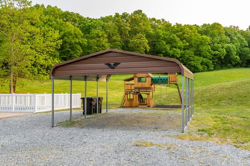 Metal carport shelter beside a wooden children's play structure