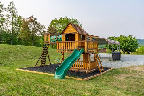 Wooden play structure with a slide beside a metal carport shelter