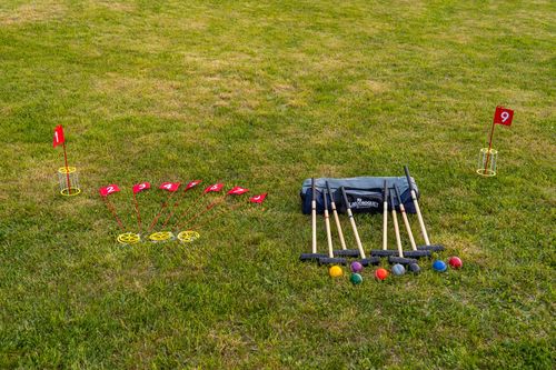 Lawn game set with croquet mallets, colored balls and numbered flags on the grass