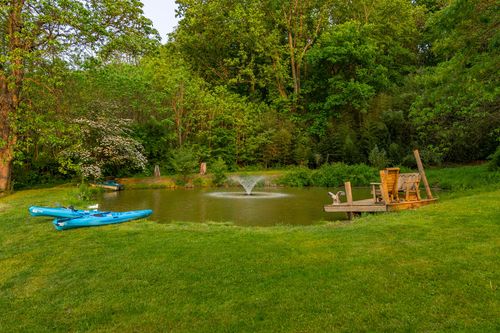 Pond with a fountain, wooden dock and kayaks along the grassy shore