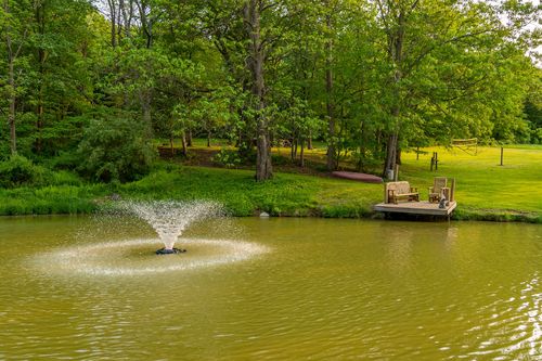 Pond with a spraying fountain bordered by a grassy lawn and wooden dock