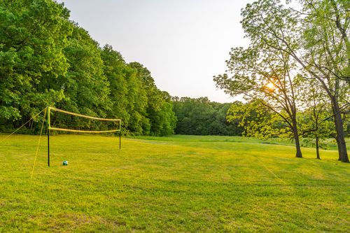 Volleyball net on a grassy field at sunset with trees in the background