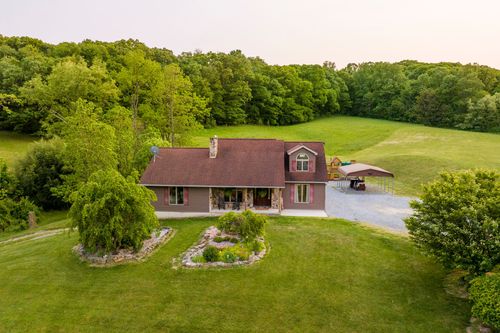 Aerial dusk view of a farmhouse with an in-ground pool, hot tub and play structure