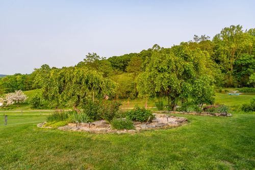 Circular garden bed with weeping willow trees and a stone border
