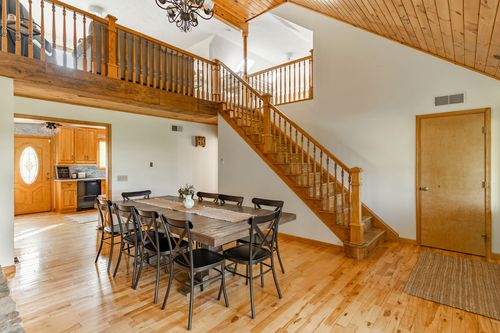 Open-concept dining area with a wood staircase, loft railing and hardwood floors