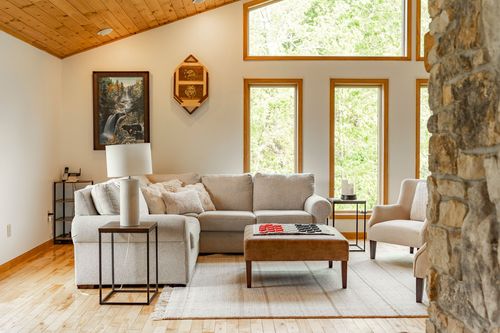 Living room with a beige sectional, vaulted wood ceiling and a checkerboard ottoman