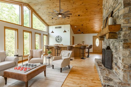 Living room with a stone fireplace, vaulted wood ceiling and bar seating