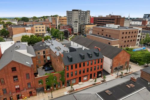 Aerial view of a red brick apartment building with a slate roof set among downtown streets