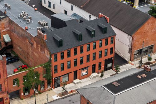 Aerial view of an ivy-covered brick ruin beside a renovated red brick apartment building
