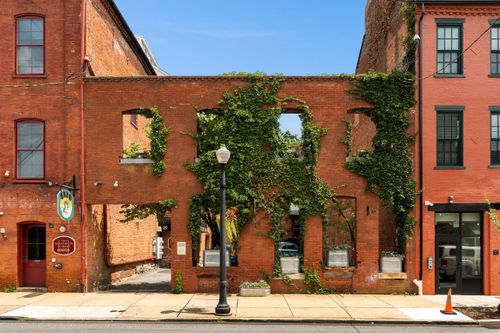Close-up of an ivy-covered brick wall with arched window openings and a vintage street lamp