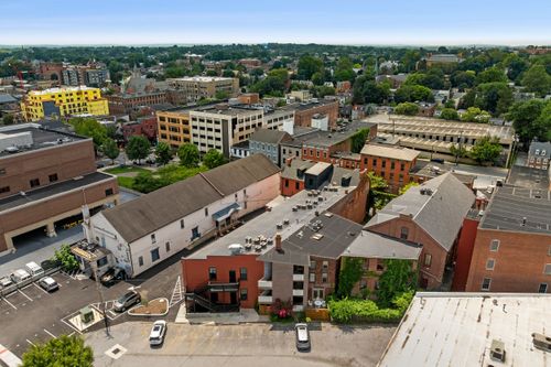 Aerial view of a downtown block with mixed rooftops, a yellow building and distant church spires