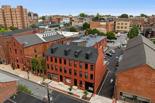 Aerial view of a renovated red brick loft building with dormer windows amid the downtown skyline