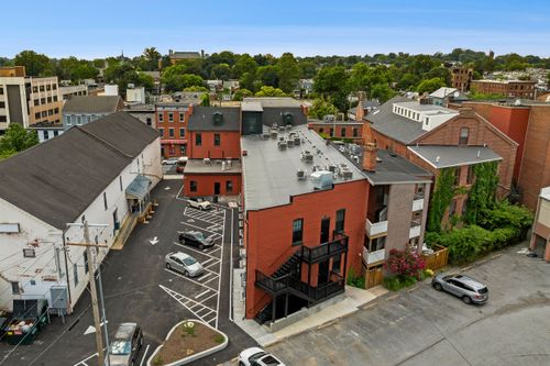 Aerial view of a brick apartment building with wrought-iron balconies and a rear parking court