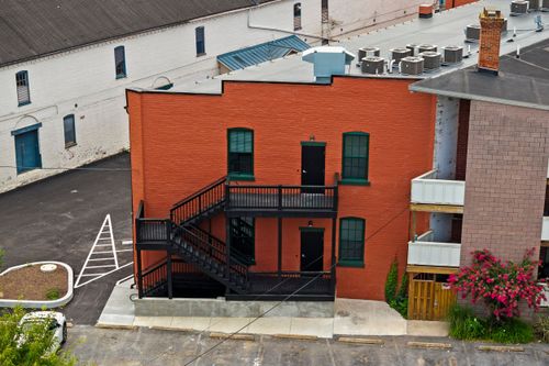Rear elevation of a rehabbed orange brick building with black exterior stairs and balcony
