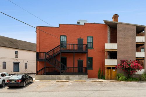 Renovated brick apartment building exterior with black metal balconies and street parking