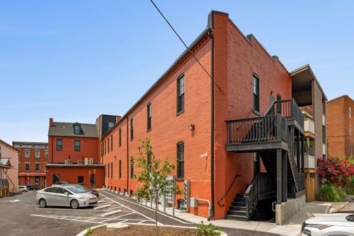 Side elevation of a red brick loft building with dark trim windows and a rear stairway