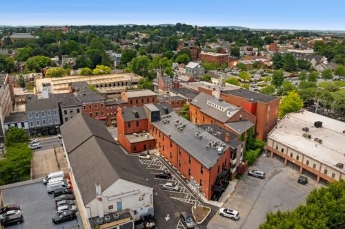 Aerial view of a mixed brick and stone downtown block with rooftop dining and courtyard parking