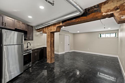 Basement kitchenette with dark cabinets, stainless appliances and an exposed rough-hewn wood beam