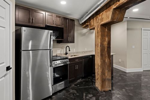 Kitchenette with dark shaker cabinets, granite counters and a rustic wood ceiling beam