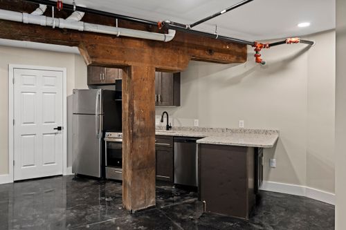 Kitchenette with a reclaimed wood support beam, stainless refrigerator and polished concrete floor
