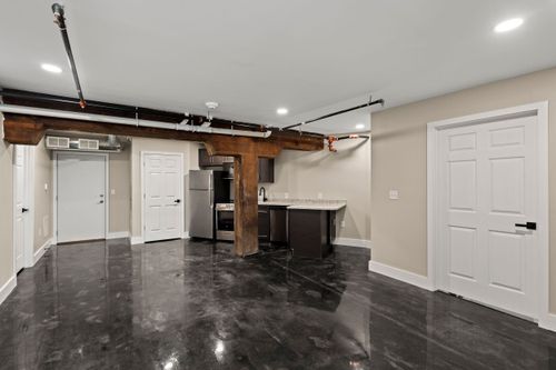 Loft-style living space with a kitchen island, exposed wood beam and glossy black flooring