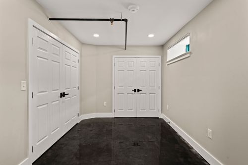 Bedroom with white double closet doors, dark polished flooring and neutral walls