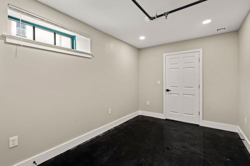 Bedroom with a teal-trimmed window, white paneled door and glossy black flooring