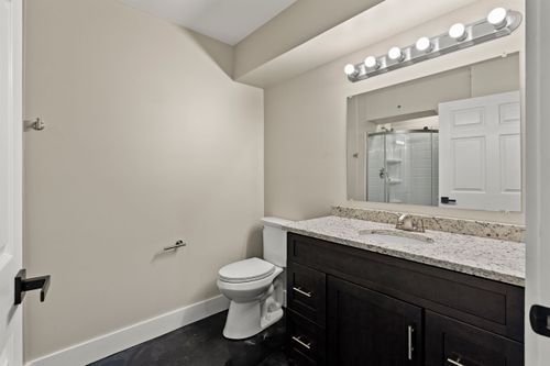 Bathroom with a dark wood vanity, granite counter and a mirror reflecting a glass shower