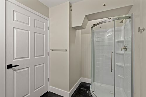 Bathroom with a curved frameless glass shower enclosure and white subway tile