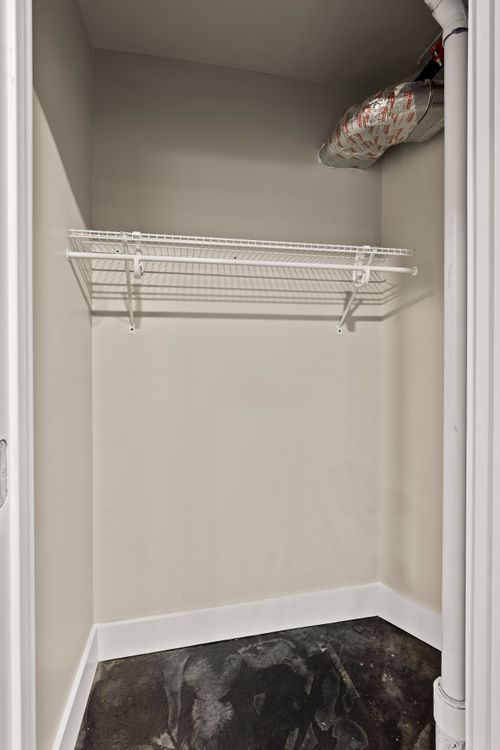 Empty walk-in closet with a white wire shelving unit and dark flooring