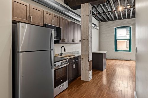 Loft kitchen with exposed brick walls, wood ceiling joists and hardwood flooring