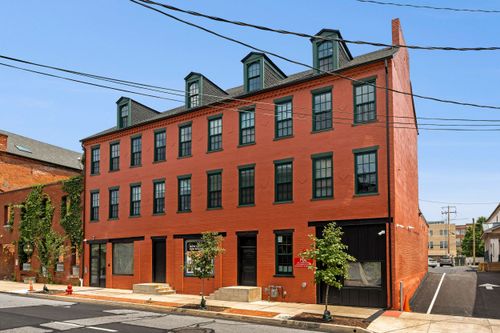 Renovated four-story brick building with black-trimmed windows, dormers and street-level storefronts