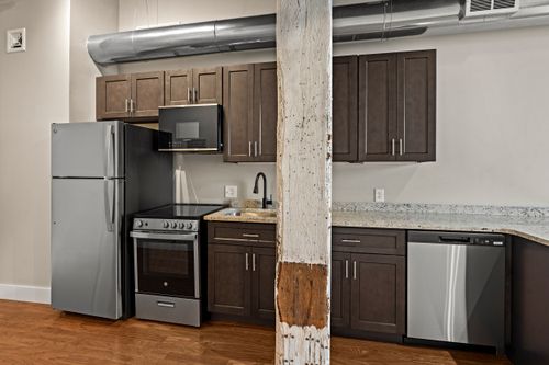 Kitchen with dark cabinetry, stainless appliances and a whitewashed exposed wood support post