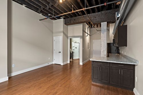 Loft living space with exposed rafters, a white column and a corner kitchenette