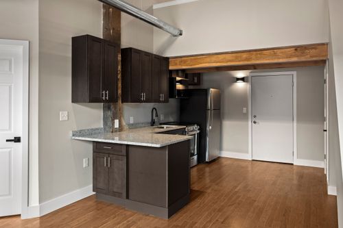 Compact kitchen with dark cabinetry, a stainless refrigerator and an exposed wood ceiling beam