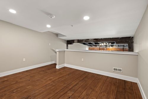 Loft mezzanine with a half-wall railing and an exposed brick chimney accent