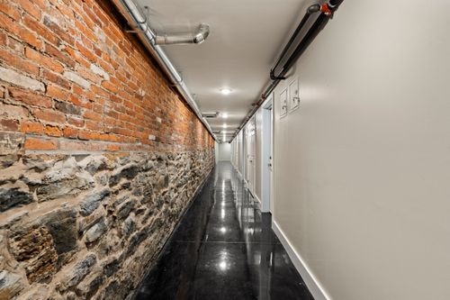 Corridor with an exposed brick and stone wall above glossy black flooring